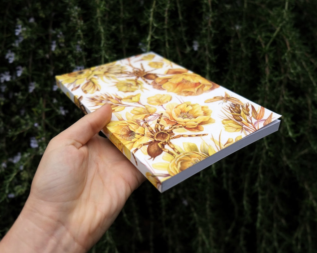 Blank notebook with repeating pattern of yellow flowers and tarantulas.