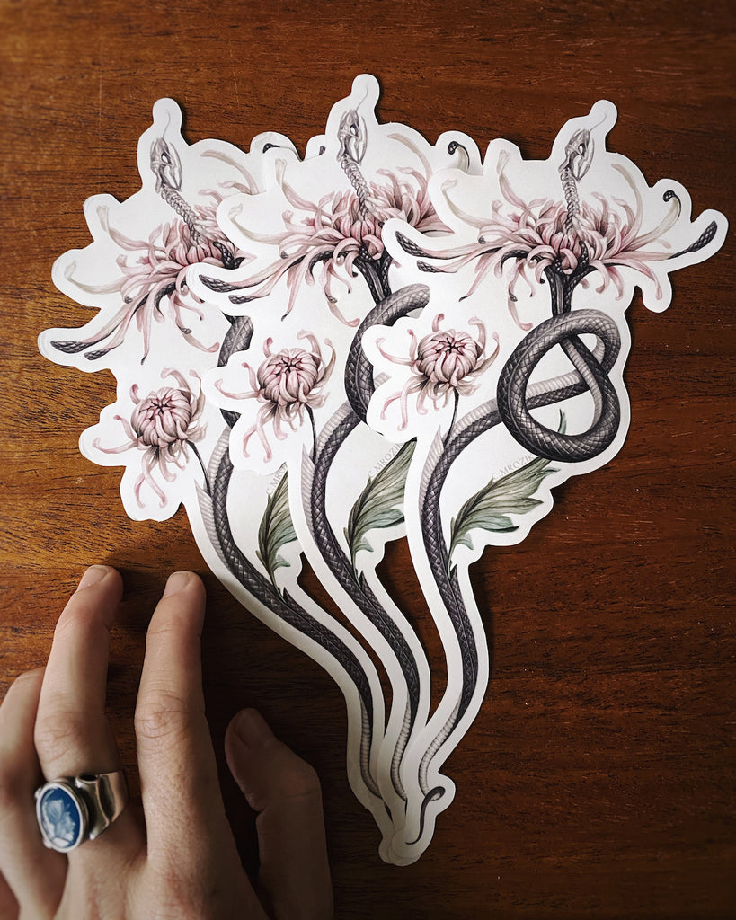 Large, clear-backed sticker with grey snake skeleton coming out of a pink chrysanthemum.