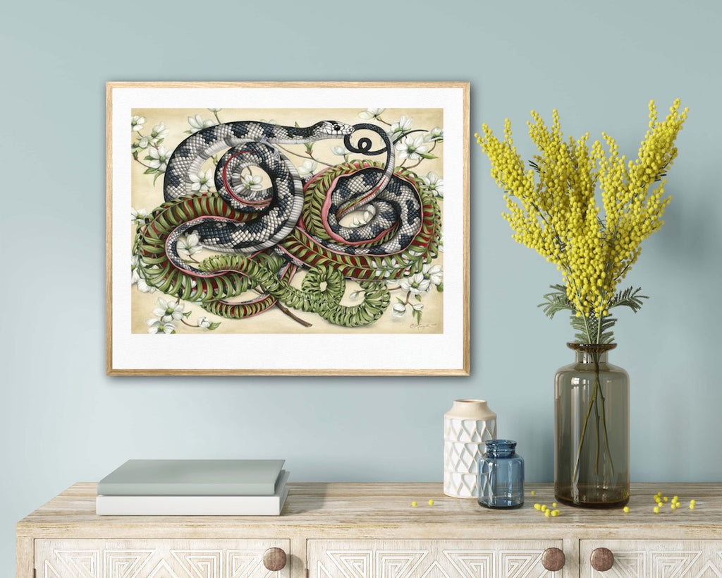 Art print of a black and white snake entwined with a snake skeleton made of ferns, surrounded by white dogwood flowers on a cream background.