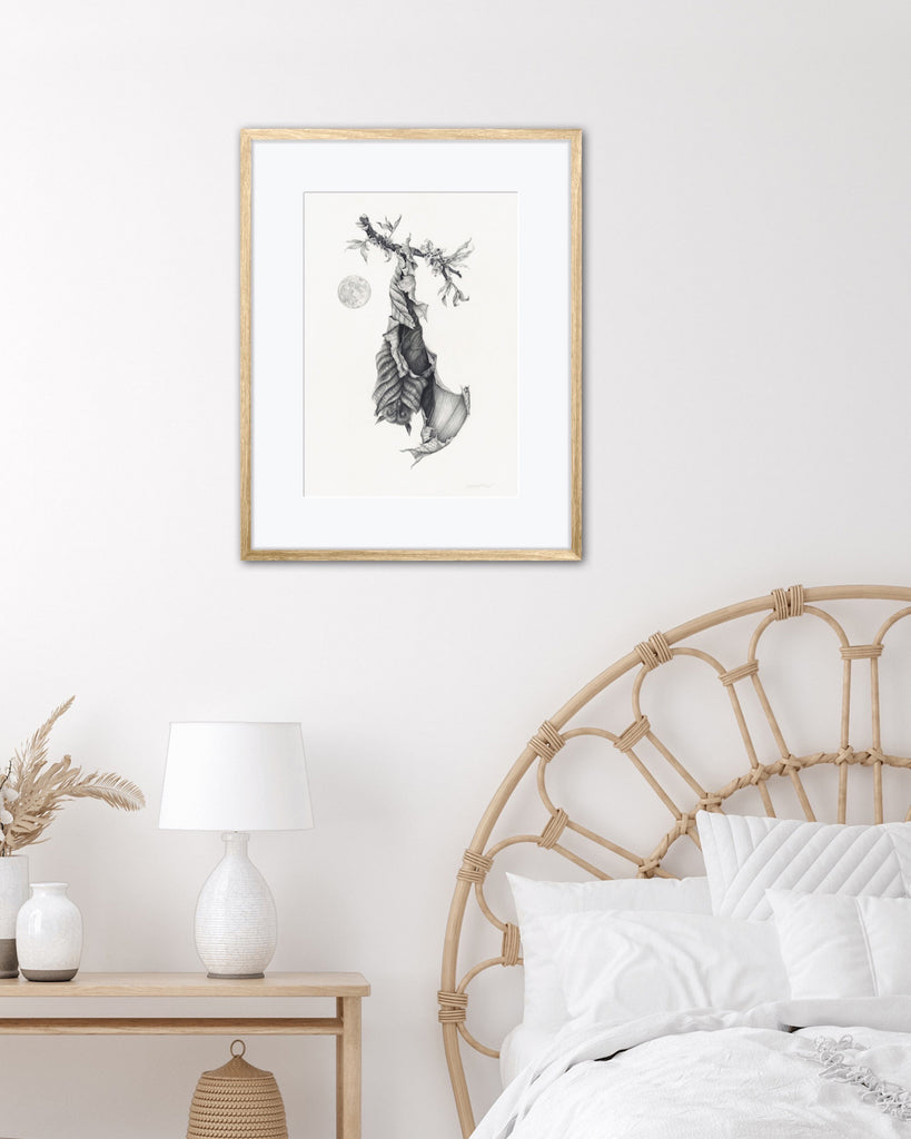 Art print of a graphite bat with leaves for wings, hanging upside down next to a full moon.