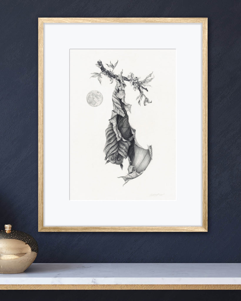 Art print of a graphite bat with leaves for wings, hanging upside down next to a full moon.