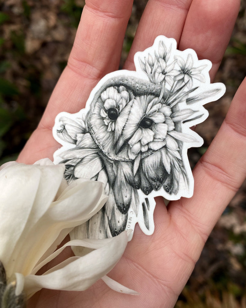 Small matte sticker with a graphite drawing of an owl head made of flower petals on a white background.