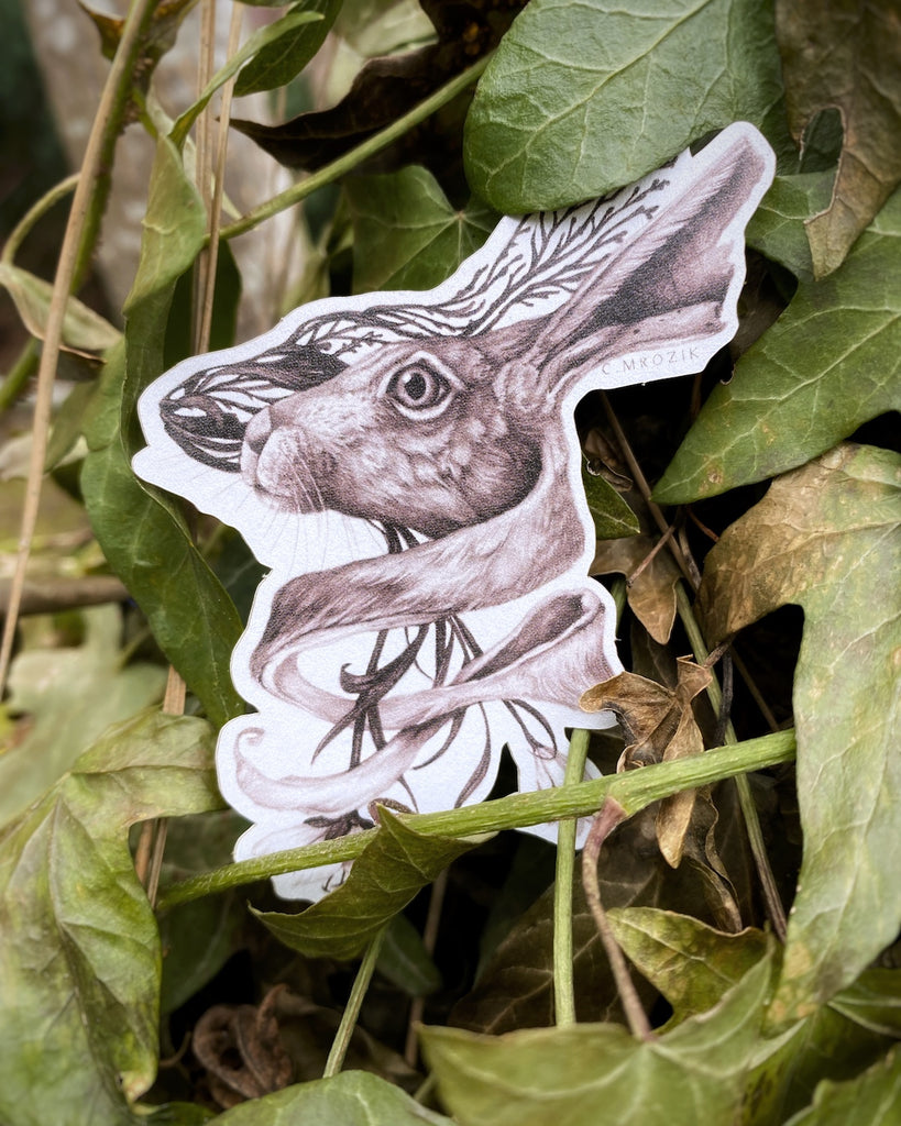 Small matte sticker with a sepia tone rabbit head intertwined with flower roots on a white background.