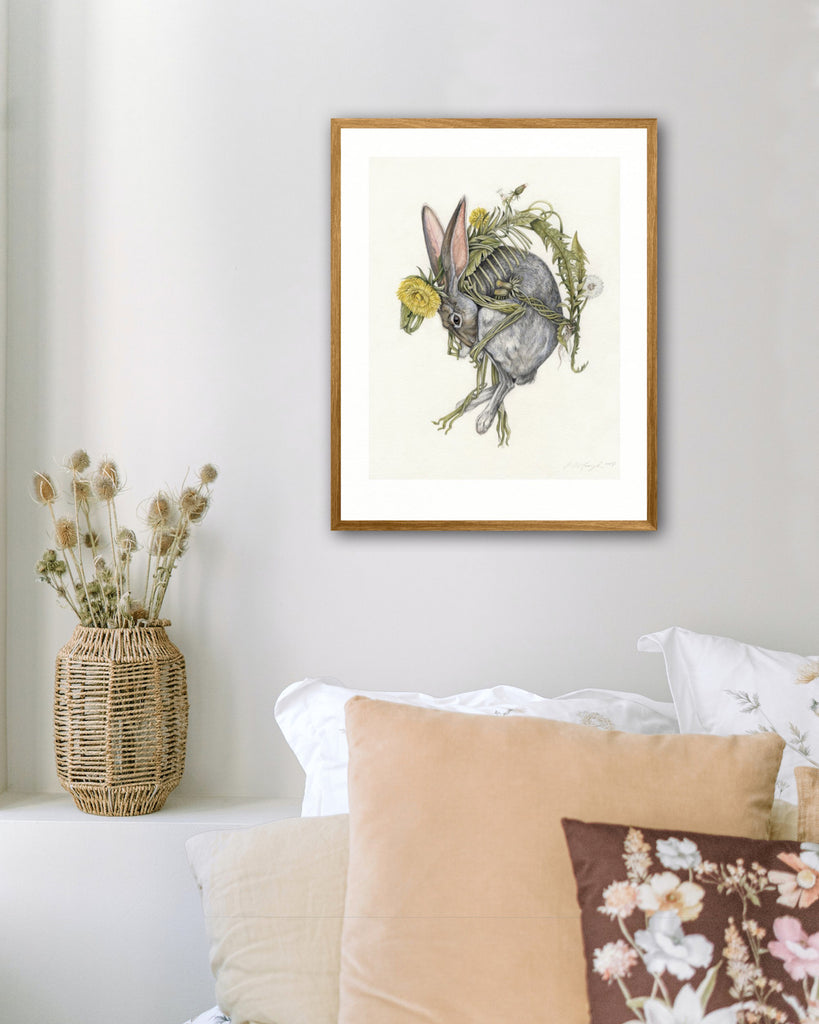 Art print of a gray rabbit curled around intertwining dandelion flowers on a cream background.