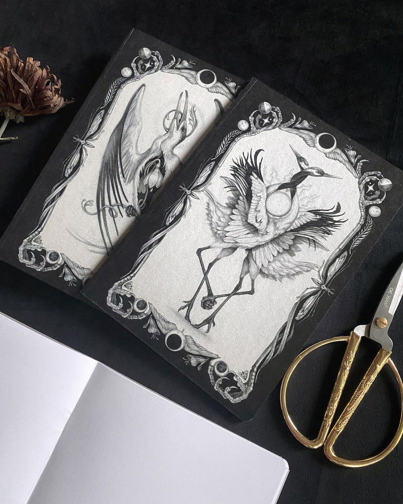 Set of three blank notebooks featuring black and white, tarot-themed illustrations of birds on the cover.