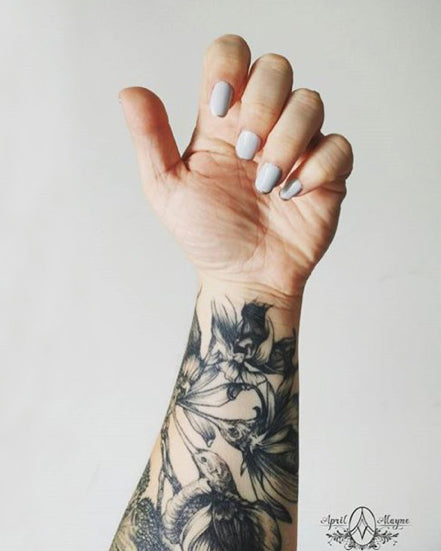 A white person’s arm with a sleeve tattoo based on artwork by Christina Mrozik.