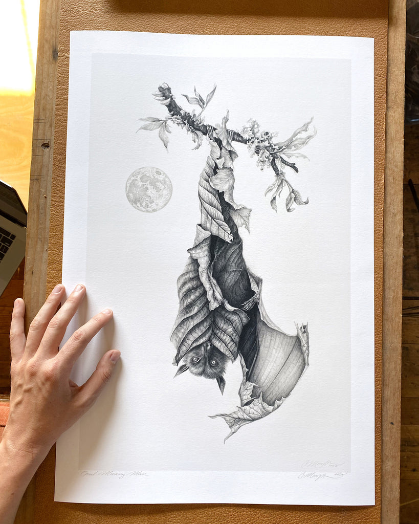 Art print of a graphite bat with leaves for wings, hanging upside down next to a full moon.