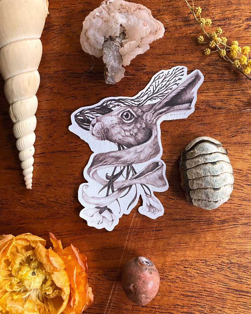 Small matte sticker with a sepia tone rabbit head intertwined with flower roots on a white background.