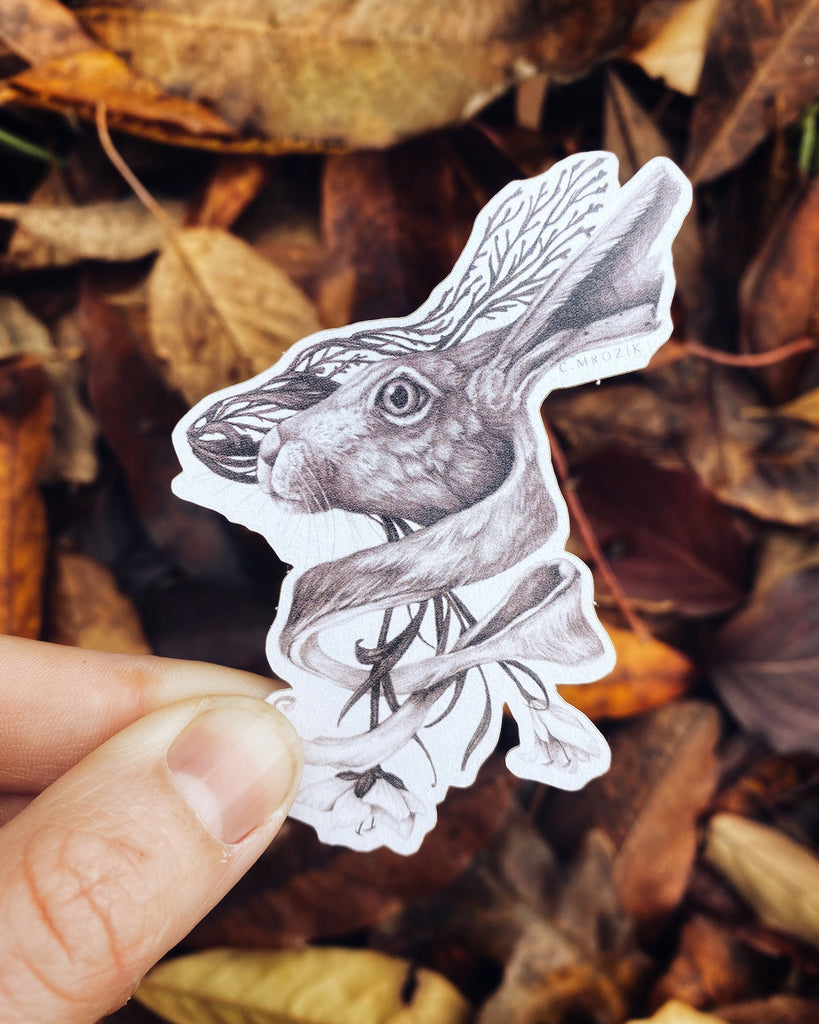 Small matte sticker with a sepia tone rabbit head intertwined with flower roots on a white background.